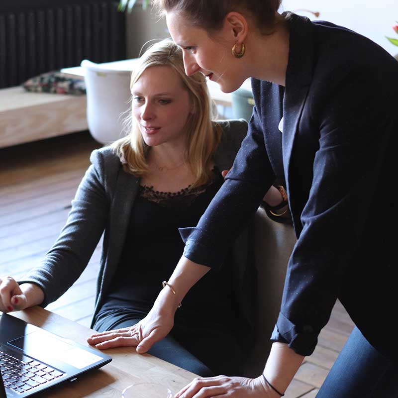 Three people gathered around a screen displaying data and charts, with a magnifying glass and target icon representing book marketing services.