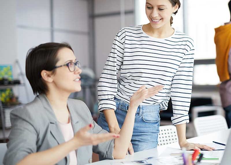 Two women collaborating on book editing, with a pencil icon indicating editing services.