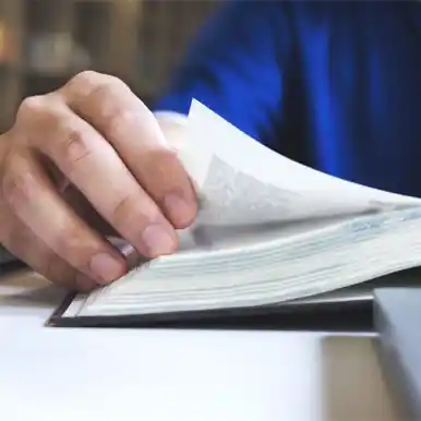 Hands turning pages of a physical book, representing standard publishing.