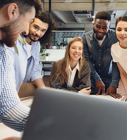 A diverse group of people looking at a laptop and smiling, possibly discussing book marketing services.