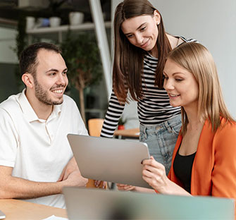 Three people looking at a tablet, possibly discussing book writing services and creative ideas.